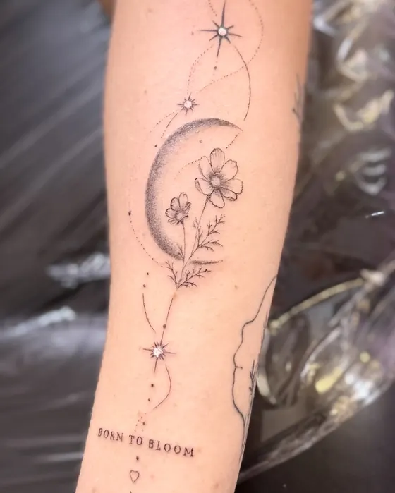 Mond mit Blüten, Sternen und dem Schriftzug „Born to bloom“ am Unterarm