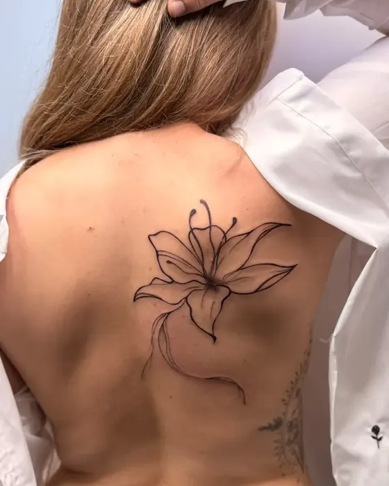 Große florale Fine Line: Lilie mit geschwungenem Stiel auf dem Schulterblatt