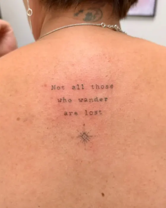 Schriftzug „Not all those who wander are lost“ mit kleinem Stern zwischen den Schulterblättern
